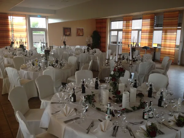 Eingedeckte Tische mit Gläsern und Blumenschmuck im Festsaal des Hotel Aramis