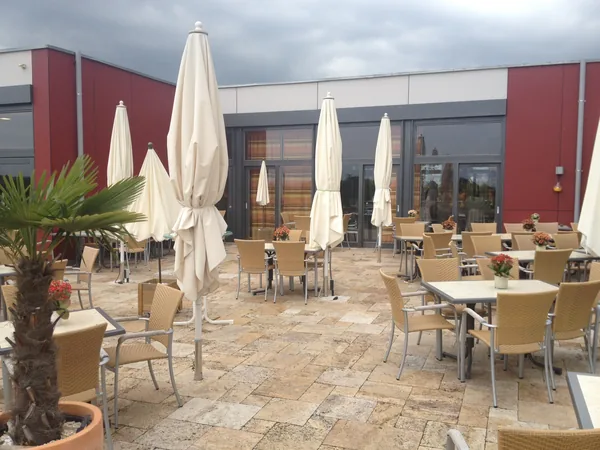 Terrasse mit Tischen und Sonnenschirmen am Hotel Aramis