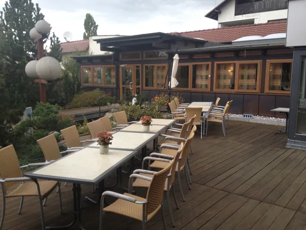 Holzterrasse mit gedeckten Tischen am Gebäude des Hotel Aramis