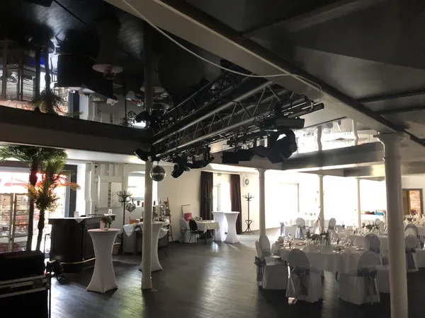 Saal Kuhstall mit Lichttraversen und Stehtischen im Hofgut Domäne