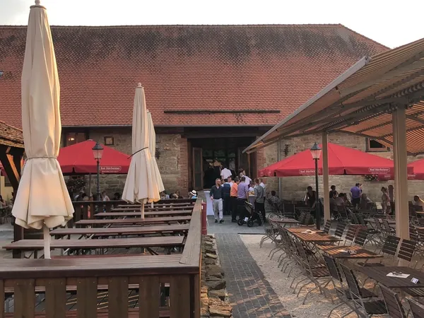 Biergarten mit Sonnenschirmen vor der Scheune am Hofgut Domäne