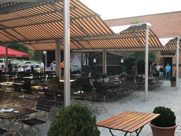 Überdachter Biergarten mit Holztischen am Hofgut Domäne