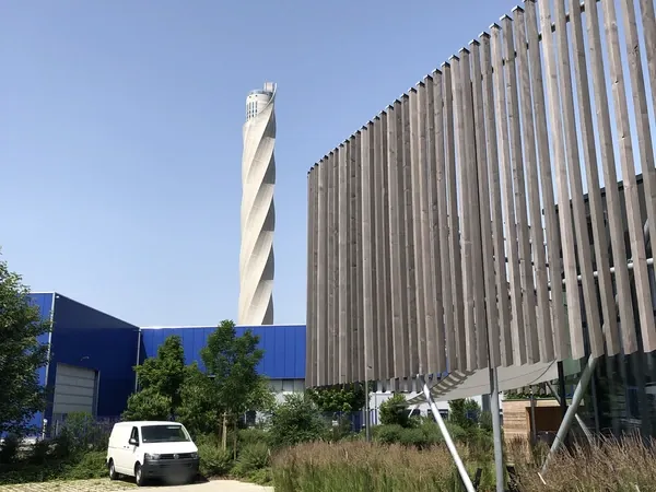 Außenansicht mit Holzlamellen und Testturm im Hintergrund an der Event Schneiderei