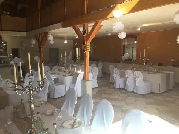 Saal mit Holzstützen, Kerzenleuchtern und weißen Stuhlhussen in Gänßle's Schuppen