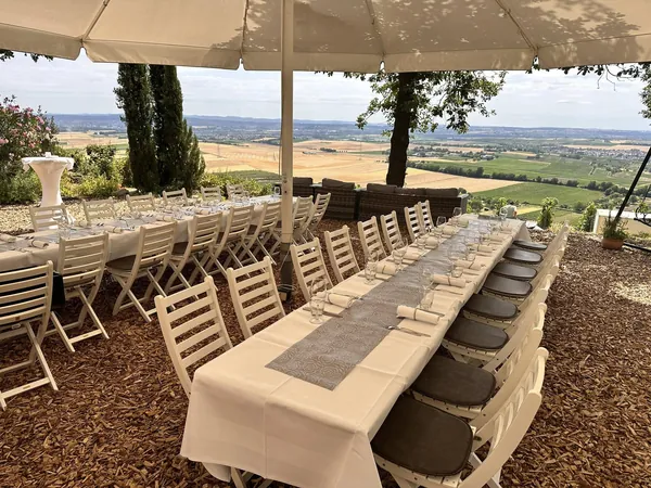 Lange gedeckte Tafel mit weißen Stühlen auf der Terrasse der Heuchelberger Warte
