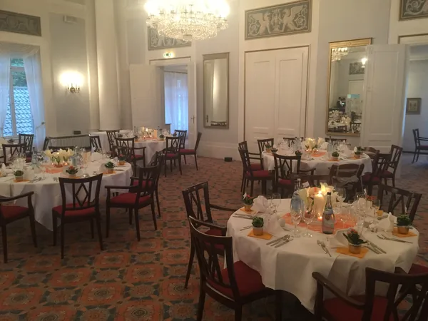 Runde Tische mit roten Stühlen im Saal des Hotel Therme