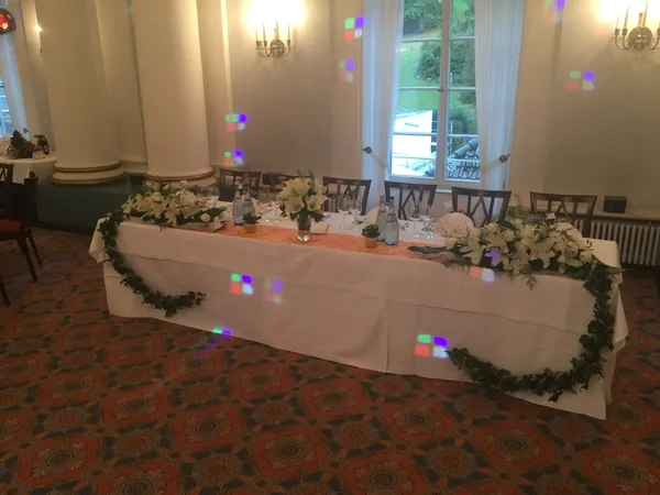Gedeckte Brauttafel mit Blumengirlande im Saal des Hotel Therme