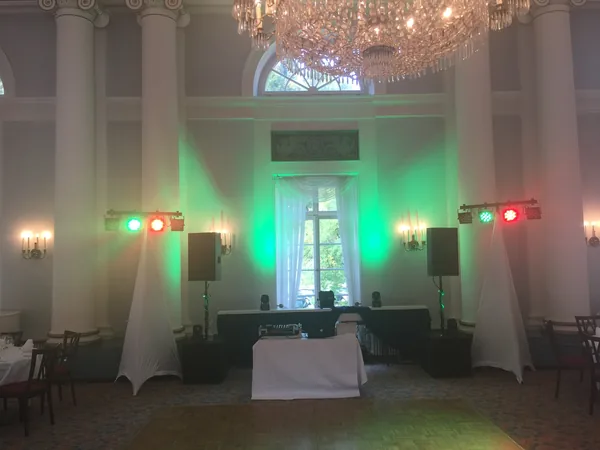 DJ-Pult mit grünem Licht vor hohen Fenstern im Hotel Therme
