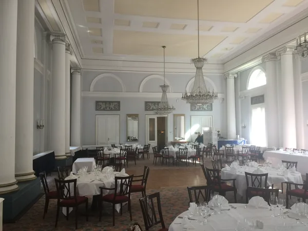 Säulensaal mit Kronleuchtern und gedeckten Tischen im Hotel Therme