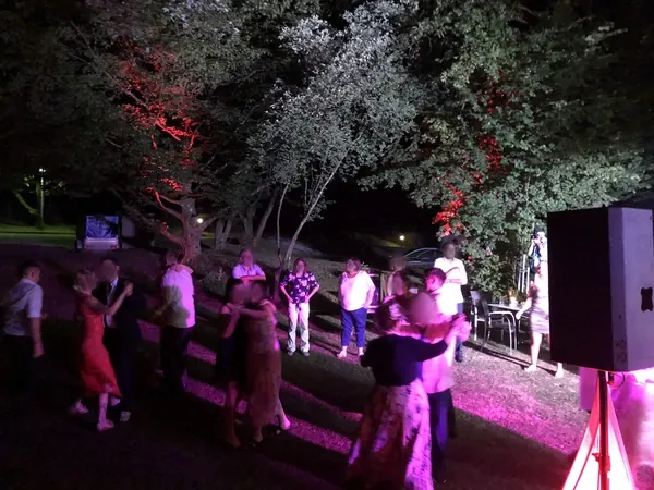 Tanzende Gäste auf der Wiese unter angestrahlten Bäumen am Kovas Balkan Restaurant