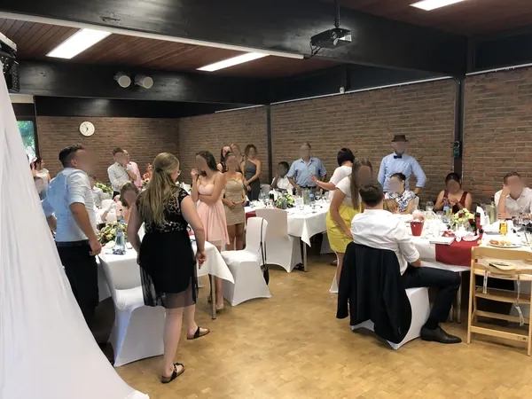 Gut gefüllter Saal mit Stuhlhussen und roten Tischläufern im Kovas Balkan Restaurant