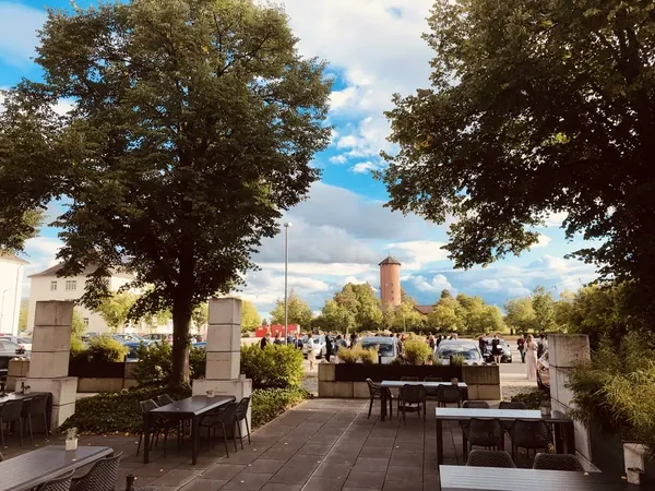 Terrasse mit alten Bäumen und Blick auf einen historischen Turm am Quartier77