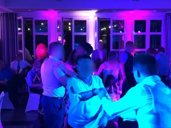 Tanzende Gäste im blau und pink beleuchteten Saal des Römerhof