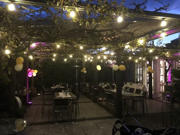 Gartenterrasse mit Weinlaub und Lichterketten am Abend im Römerhof