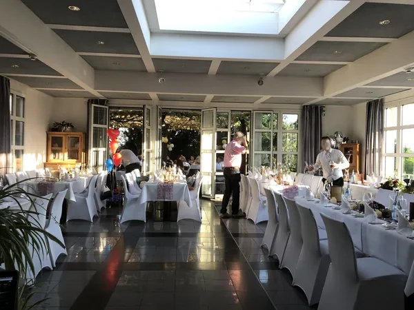 Saal mit Lichtkuppel, Stuhlhussen und geöffneten Terrassentüren im Römerhof