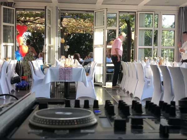 DJ-Pult mit Blick auf gedeckte Tafeln und offene Terrassentüren im Römerhof