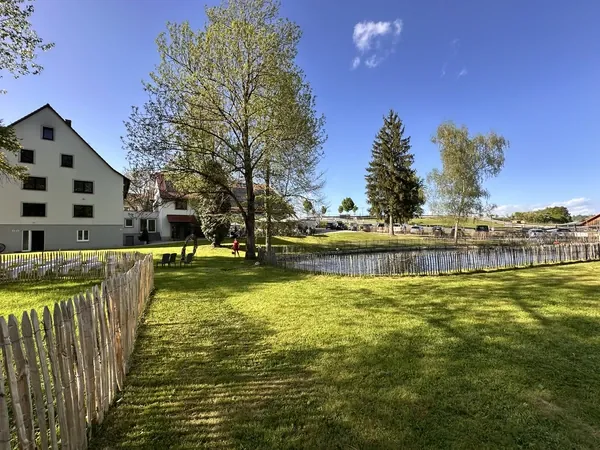 Wiese mit Holzzaun und Teich auf dem Gelände der Rötenmühle