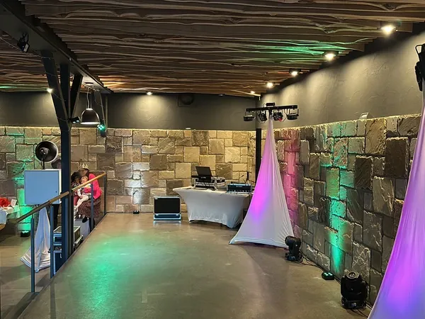 DJ-Technik und beleuchtete Natursteinwand auf der Bühne der Rötenmühle