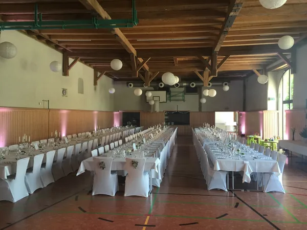 Festhalle mit langen gedeckten Tafeln und Papierlampions in der Schloss-Scheuer Baisingen