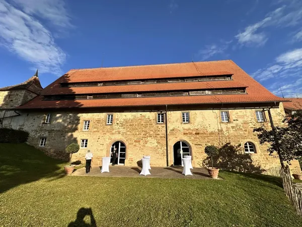 Steinernes Gebäude mit Stehtischen am Rasen des Schloss Wachendorf