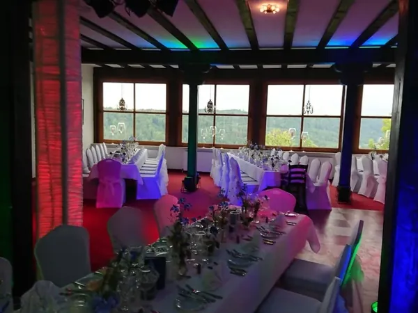 Saal mit grün beleuchtetem Fensterblick und gedeckten Tischen im Schloss Weitenburg