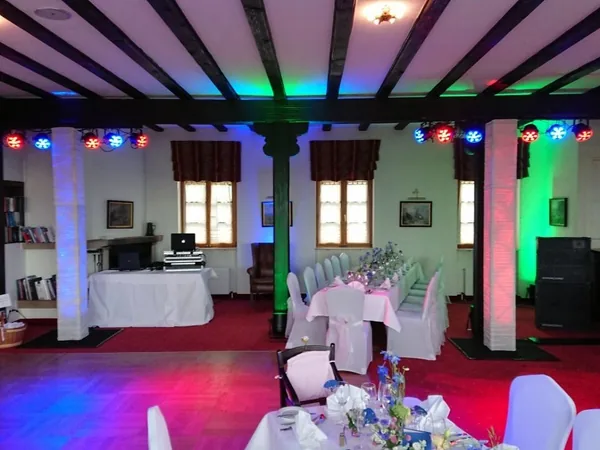 DJ-Pult mit buntem Licht und gedeckten Tischen im Schloss Weitenburg