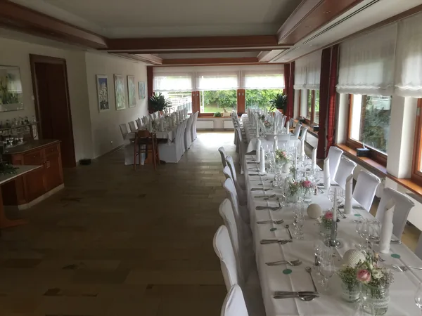 Lange Tafel mit Stuhlhussen und Blick ins Grüne im Restaurant Talblick