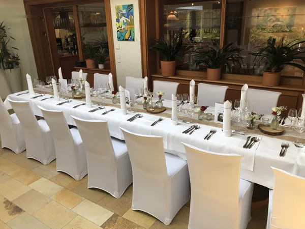 Lange Tafel mit Blumenschmuck und Kerzen im Restaurant Talblick