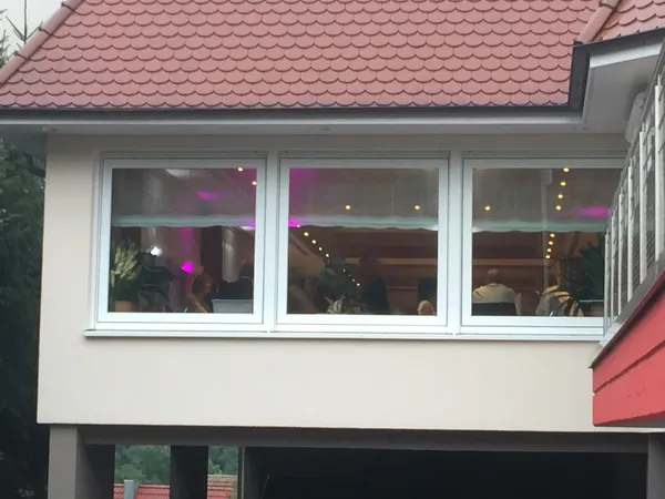 Außenansicht mit Wintergarten und rosa beleuchteten Fenstern am Restaurant Talblick