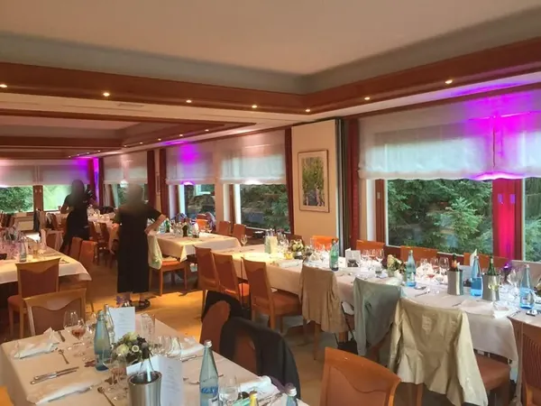 Lange Tafeln mit rosa Licht an den Fenstern im Restaurant Talblick